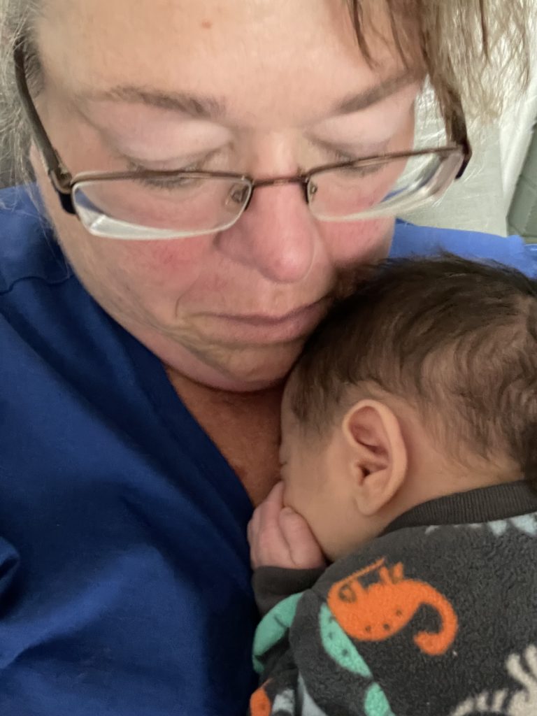A woman in glasses snuggles a small baby