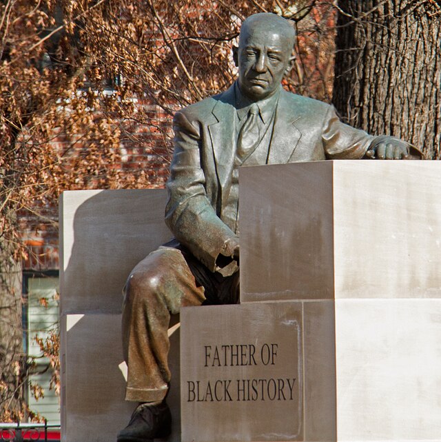 A photograph of a statue and memorial to Carter G. Woodson, with the words "Father of Black History"